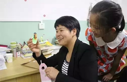 ▲9月11日中午,段雪梅拿出一学生送给她的礼物,一个彩泥娃娃给其他学生看。